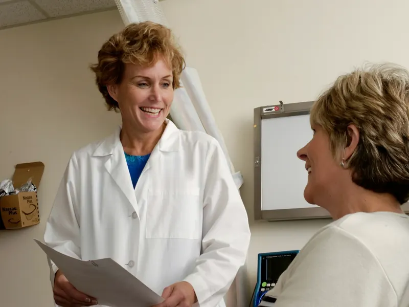 Gynecologist in a white coat talking with a patient in her office