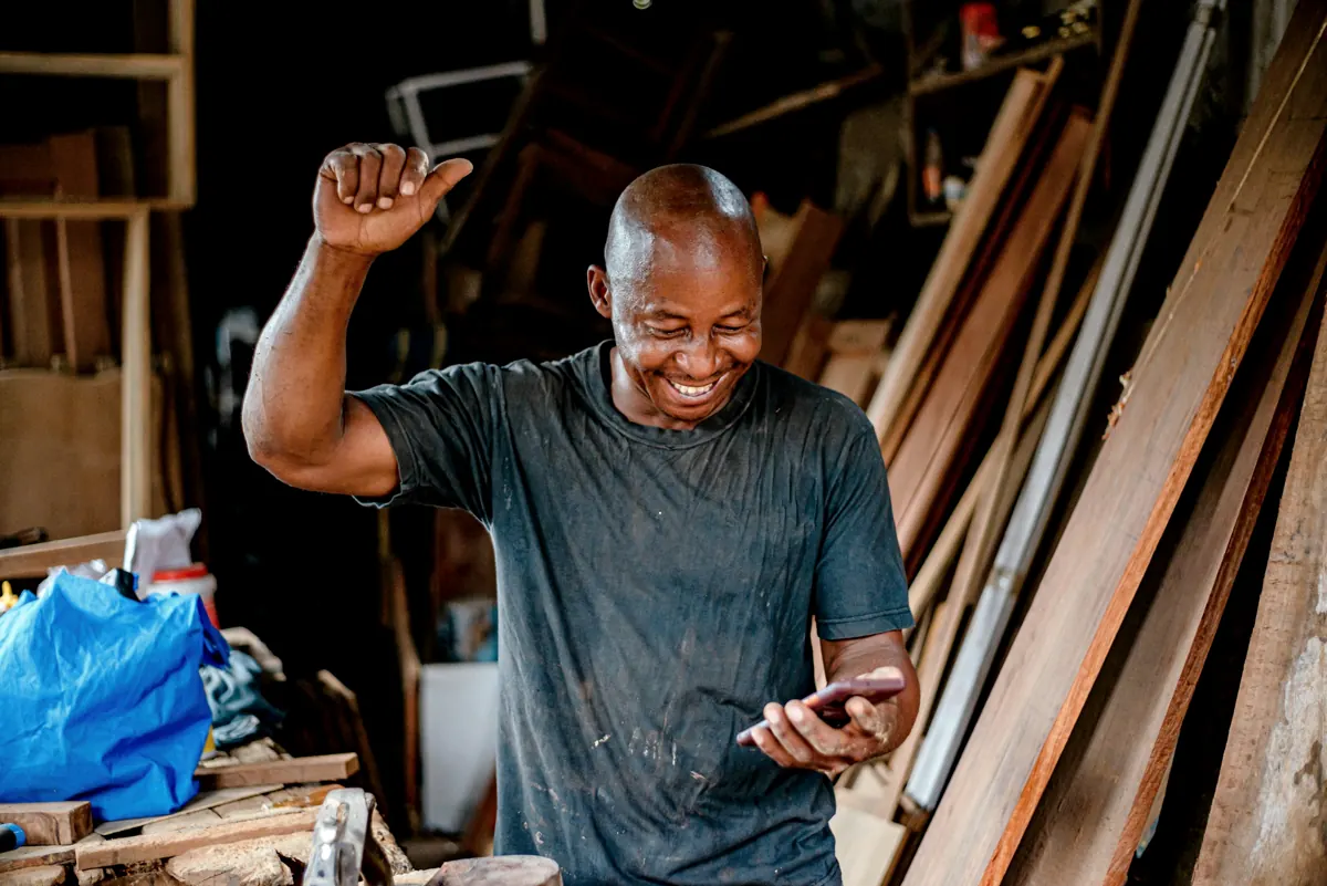 Carpentry shop owner celebrating while checking his phone